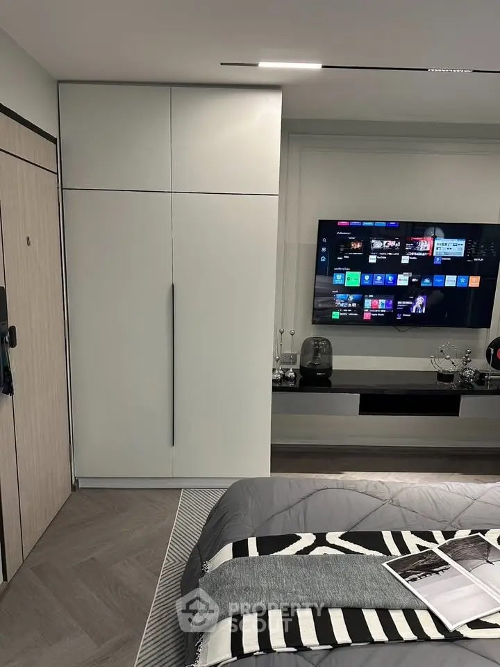 Modern bedroom with sleek wardrobe and wall-mounted TV, stylish decor