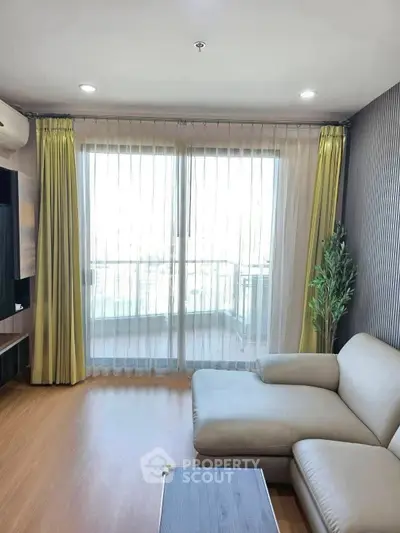 Modern living room with large windows and balcony access, featuring a stylish sofa and elegant decor.
