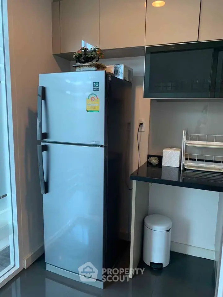 Modern kitchen with sleek refrigerator and stylish cabinetry in a contemporary apartment.