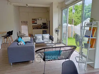 Modern living room with open layout and garden view, featuring stylish furniture and natural light.