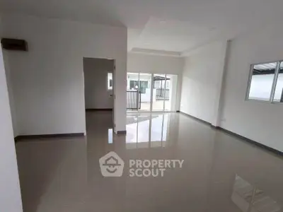 Spacious empty living room with large windows and glossy tiled floors.