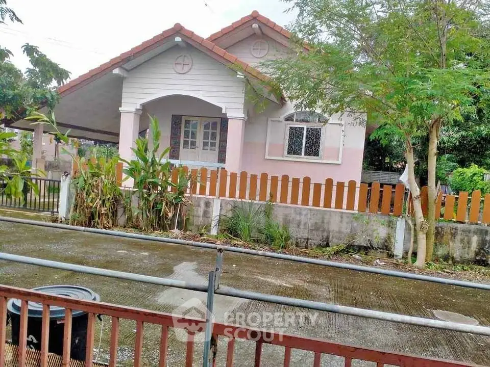 Charming single-story house with a fenced yard and lush greenery, perfect for family living.