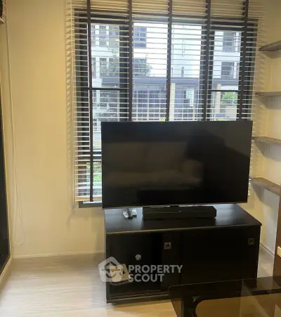Modern living room with large window and sleek TV setup in urban apartment.