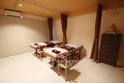 Spacious massage room with two beds, warm lighting, and elegant decor for a relaxing experience.