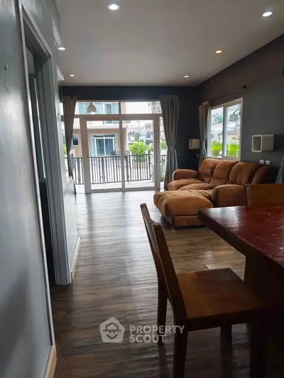 Spacious living room with modern decor and large windows opening to a balcony view.