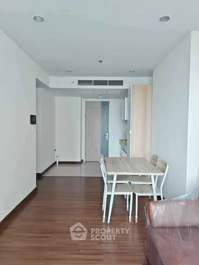 Modern apartment interior with wooden flooring and dining area, showcasing minimalist design and natural light.