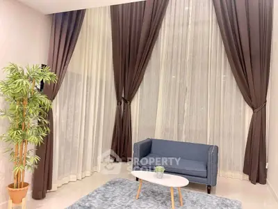 Elegant living room with high ceilings, large windows, and luxurious curtains.