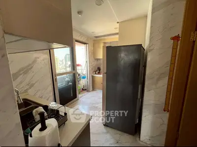 Modern kitchen with sleek appliances and marble flooring, featuring a spacious fridge and ample natural light.