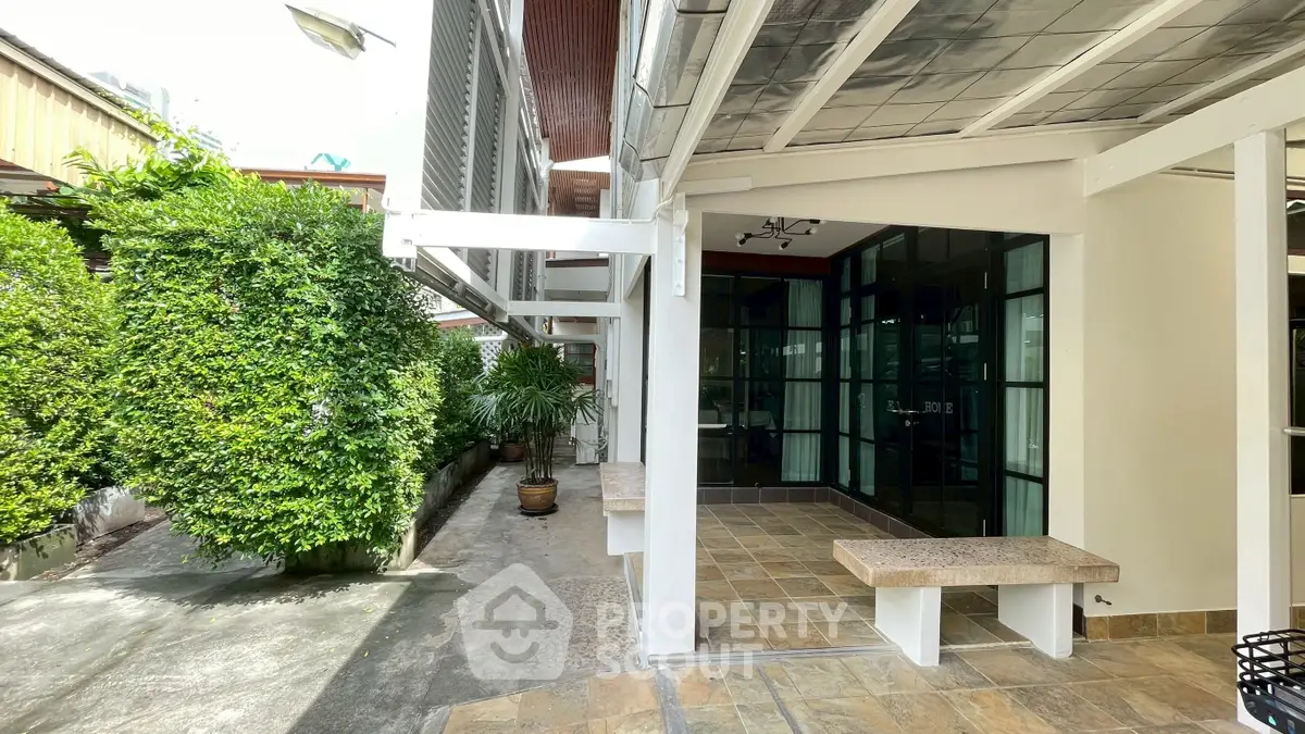 Charming outdoor patio with tiled flooring and lush greenery, perfect for relaxation and entertaining.