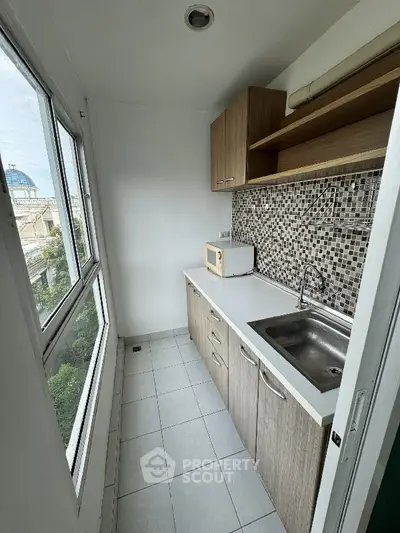 Compact kitchen with mosaic backsplash and large window offering city views