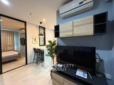 Modern living room with sleek TV setup and open view to cozy bedroom