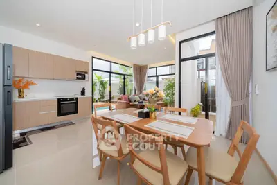 Modern open-plan kitchen and dining area with pool view, featuring sleek appliances and elegant decor.