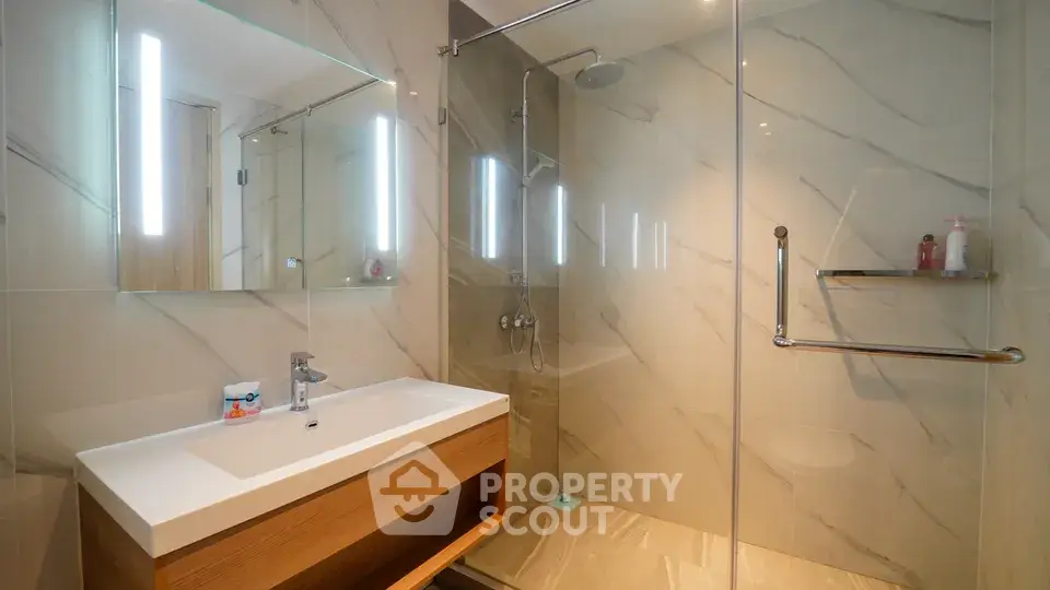 Modern bathroom with glass shower and sleek vanity in luxury apartment.