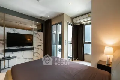 Modern bedroom with large TV and balcony access in luxury apartment