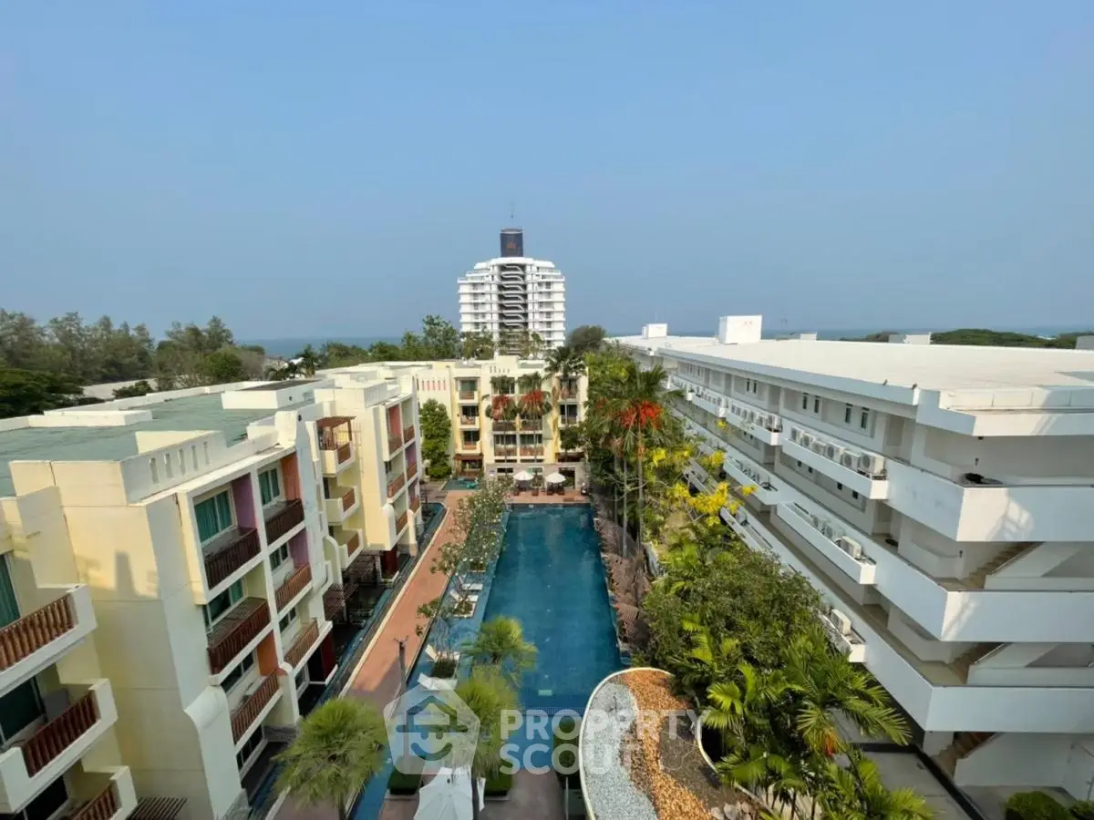 Stunning aerial view of luxury apartment complex with central pool and lush greenery.