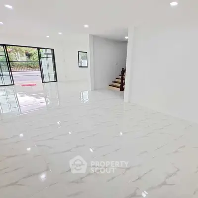 Spacious modern living room with glossy tile flooring and large windows for natural light.