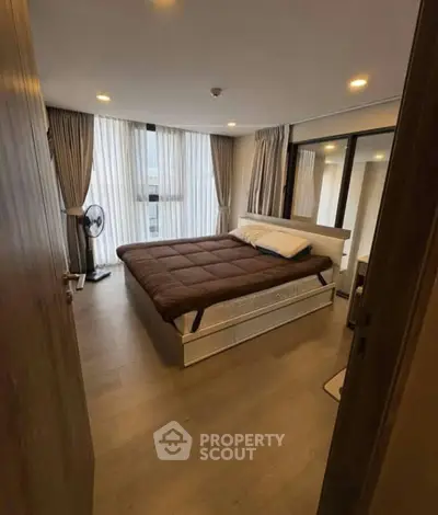 Cozy bedroom with modern decor and large windows in a stylish apartment.