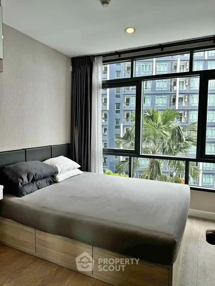 Modern bedroom with large windows offering a stunning city view, featuring a cozy bed and elegant decor.