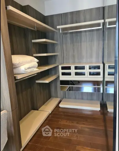 Spacious walk-in closet with wooden shelves and drawers, perfect for organized storage.