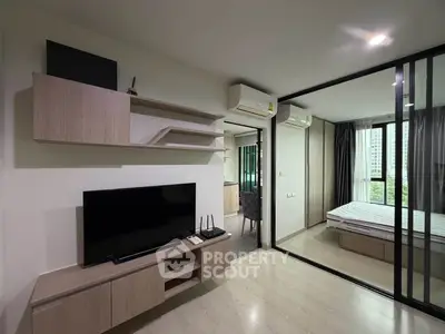Modern apartment interior with living room and bedroom, featuring sleek furniture and large windows.
