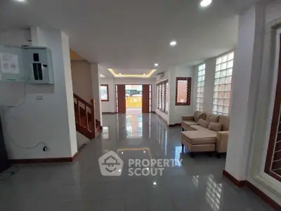 Spacious modern living room with sleek tile flooring and cozy seating area, perfect for family gatherings.