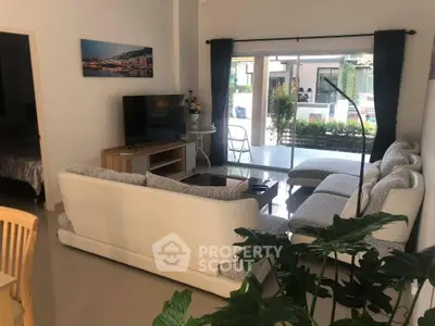 Spacious living room with modern furniture and large glass doors leading to garden view.