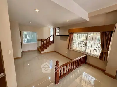 Spacious living room with elegant wooden staircase and large windows for natural light.