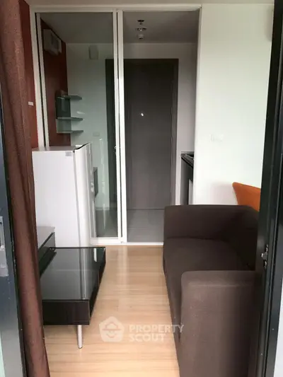 Cozy compact living room with modern furniture and kitchenette in a stylish apartment.