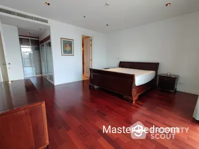 Spacious master bedroom with polished hardwood floors, large bed, and ample natural light, perfect for a luxurious living experience.