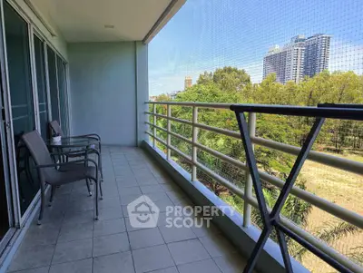 Spacious balcony with chairs offering a serene view of greenery and cityscape.
