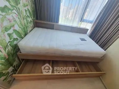 Modern bedroom with stylish bed and storage drawers, featuring a vibrant leafy wallpaper and city view.