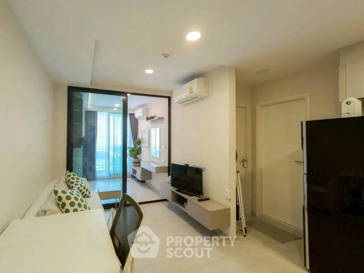 Modern living room with sleek design and natural light, featuring a compact TV setup and air conditioning.