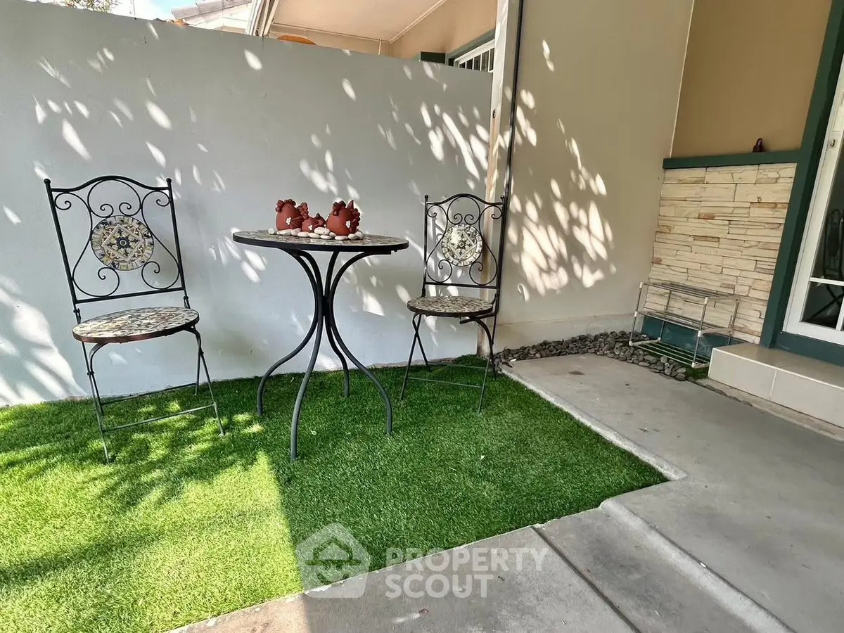 Charming outdoor patio with elegant wrought iron furniture and artificial grass.