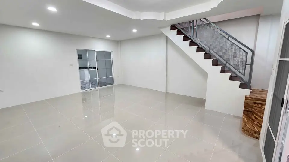 Spacious modern living room with sleek staircase and glossy tiled floor