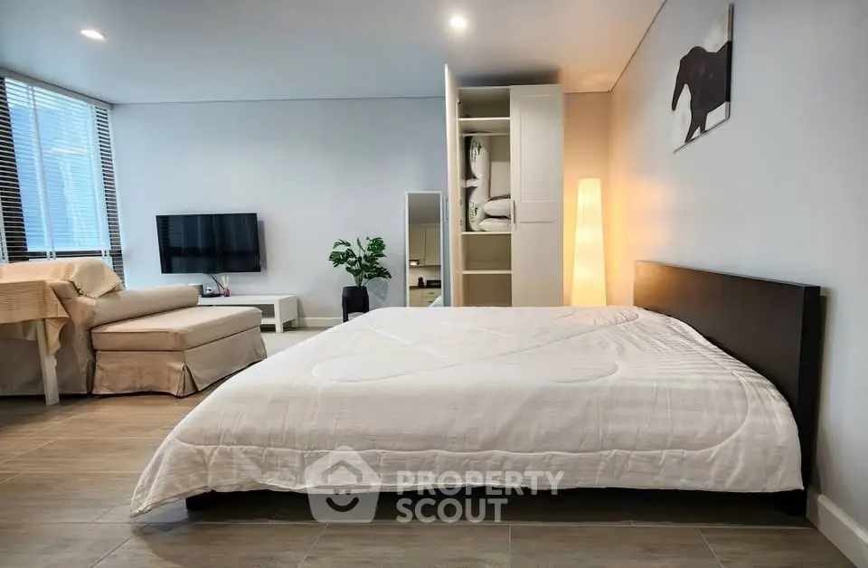 Spacious modern bedroom with cozy seating area and stylish decor