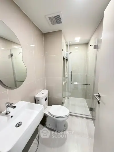 Modern bathroom with sleek fixtures and glass shower enclosure in a contemporary apartment.