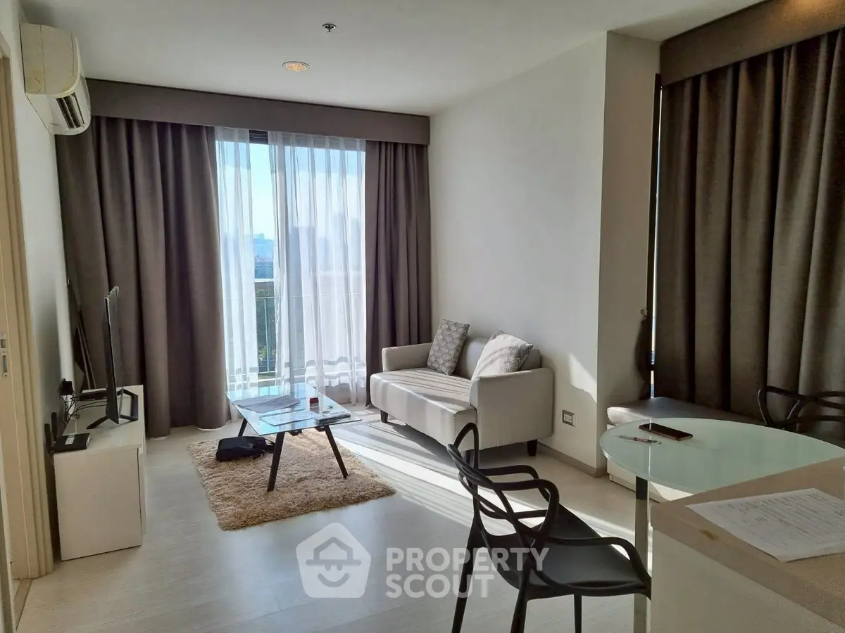 Modern living room with natural light, featuring cozy seating and a sleek TV setup, perfect for relaxation.