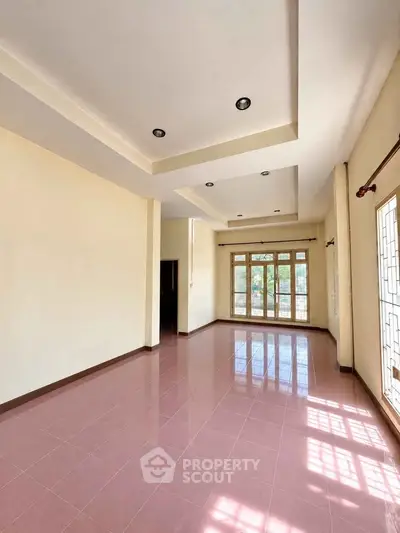 Spacious living room with large windows and elegant ceiling design, perfect for natural light lovers.