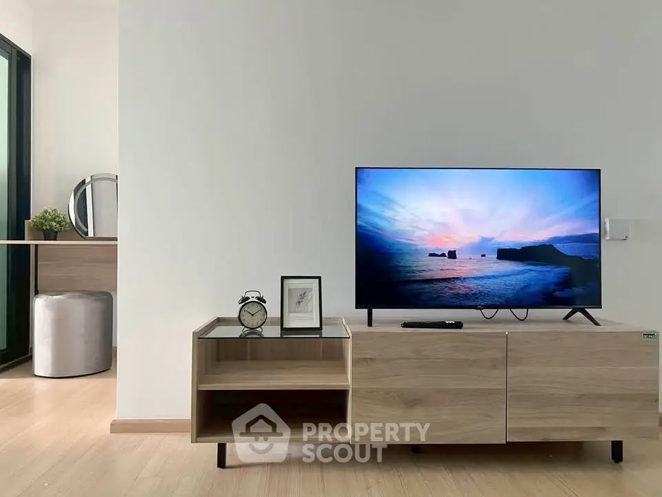 Modern living room with sleek TV stand and scenic view on screen, minimalist decor, and wooden flooring.