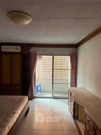 Cozy bedroom with balcony access and natural light, featuring a bed and built-in wardrobe.