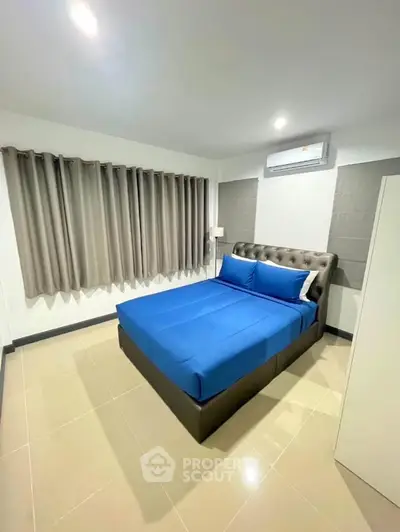 Modern bedroom with blue bedding and air conditioning, perfect for comfort and relaxation.
