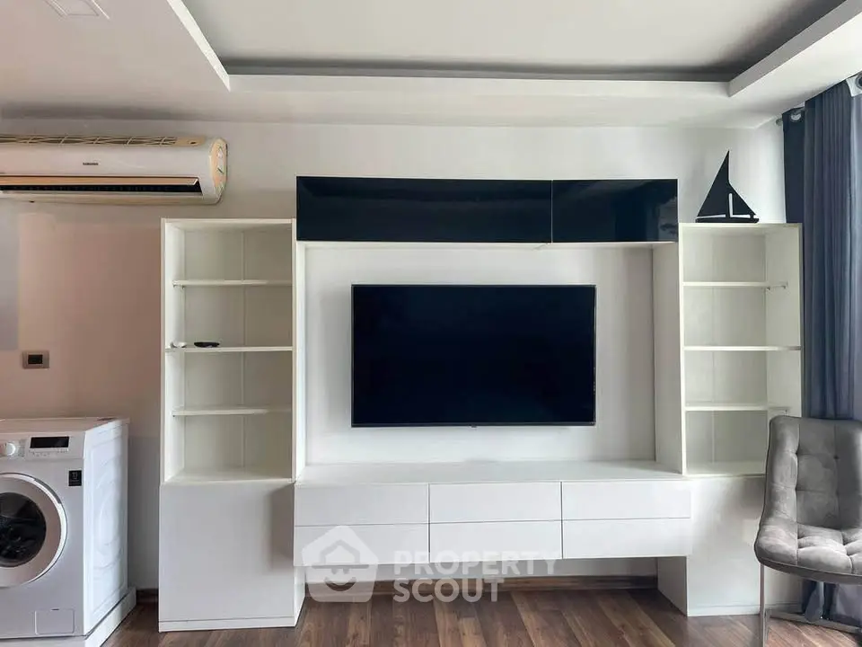 Modern living room with sleek TV unit, air conditioning, and washing machine in stylish apartment.
