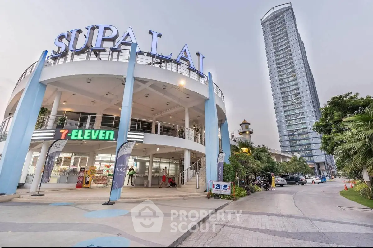 Modern commercial building with retail shops and high-rise residential tower in urban setting.