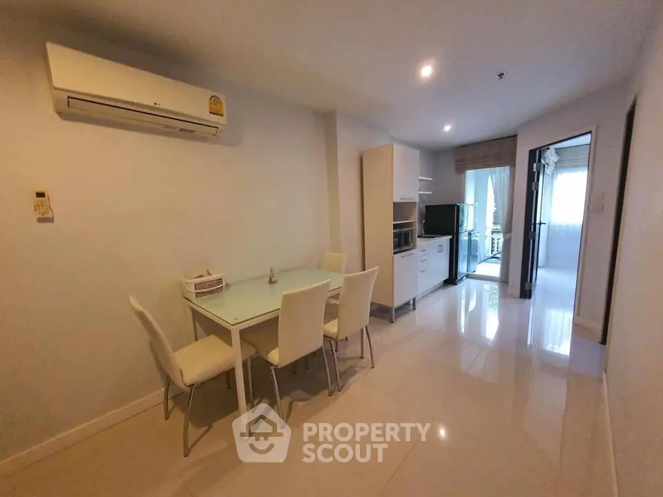 Modern dining area with sleek white furniture and air conditioning in a bright apartment.