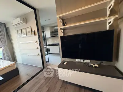 Modern apartment interior with sleek living room and kitchen, featuring a large TV and stylish decor.