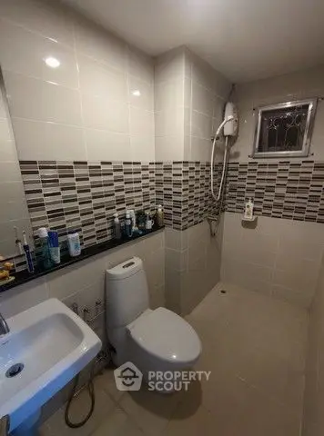Modern bathroom with sleek tiles and shower area in a contemporary home.