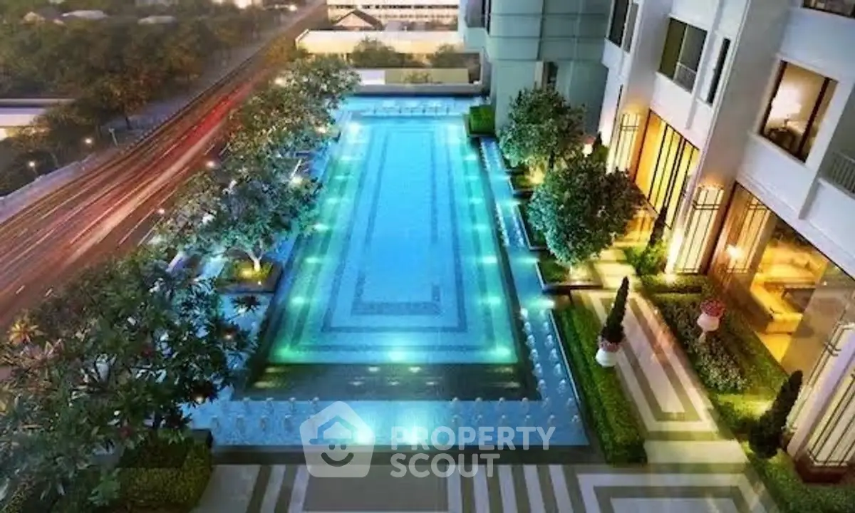 Luxurious residential building with illuminated swimming pool and lush greenery, perfect for relaxation and leisure.