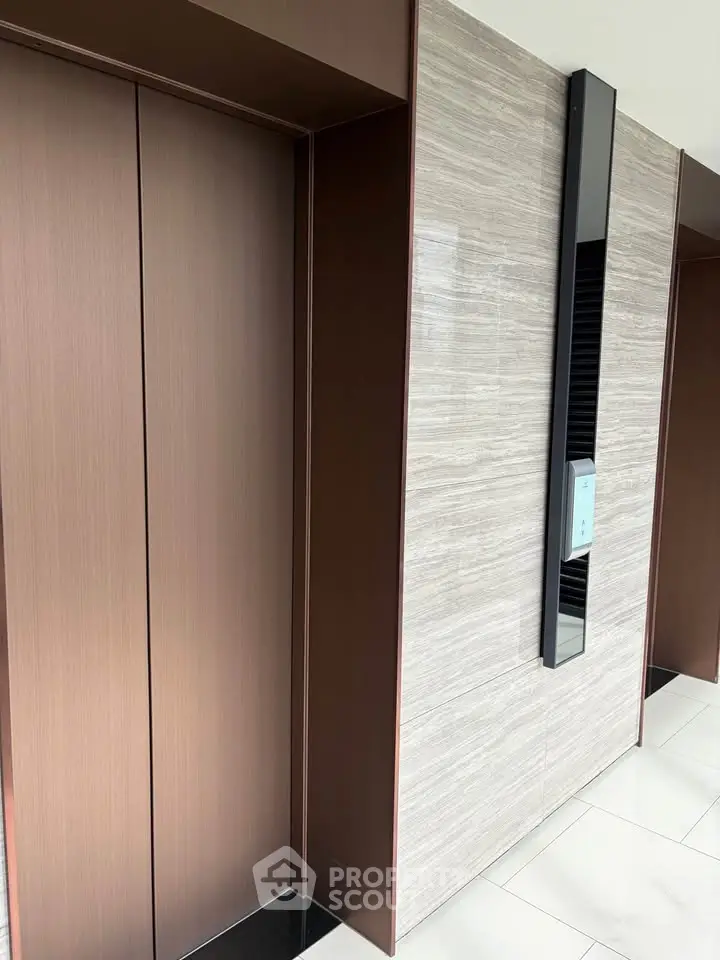 Modern elevator lobby with sleek design and marble accents in a luxury building.