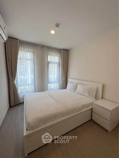 Modern bedroom with natural light and minimalist decor, featuring a comfortable bed and stylish curtains.