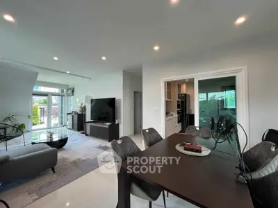 Spacious modern living room with dining area and large windows offering natural light and garden view.